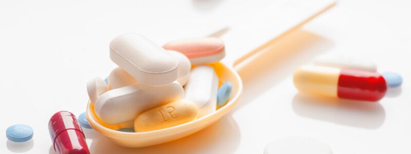 Various tablets and pills arranged on a spoon