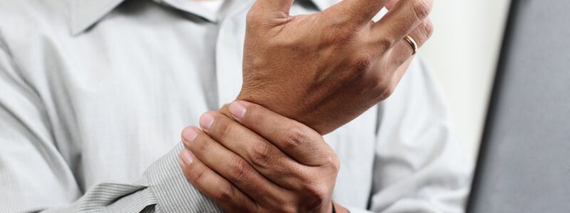 Mann mit Gelenkschmerzen in der Hand