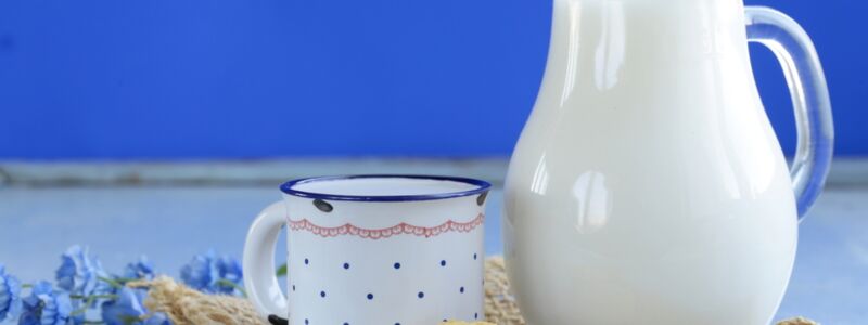 Glass jug with milk on a wooden tray