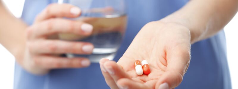 Woman about to take two capsules with water