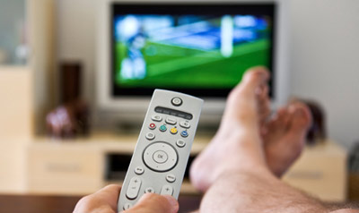 Feet up; with remote control on couch in front of the TV