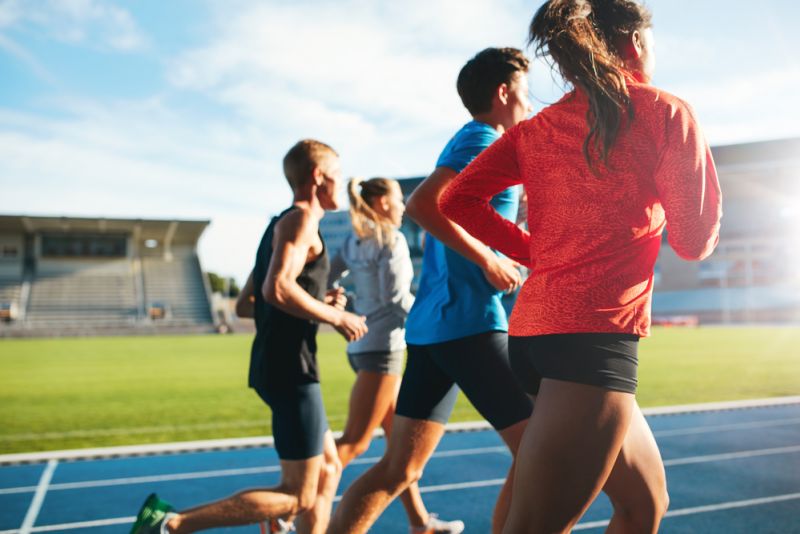 Four athletes run on a track